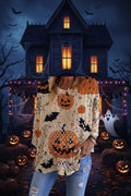 A woman wearing a cream-colored knit sweater with a Halloween print featuring orange pumpkins, black bats, and spiderwebs, paired with blue jeans.