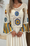 A woman wearing a cream crochet knit top with colorful circular and striped crochet details, paired with light-wash denim shorts.
