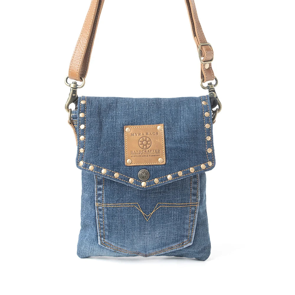Myra Dahlia Denim Crossbody Bag with blue upcycled denim, brass stud accents, leather flap detail, and shoulder strap