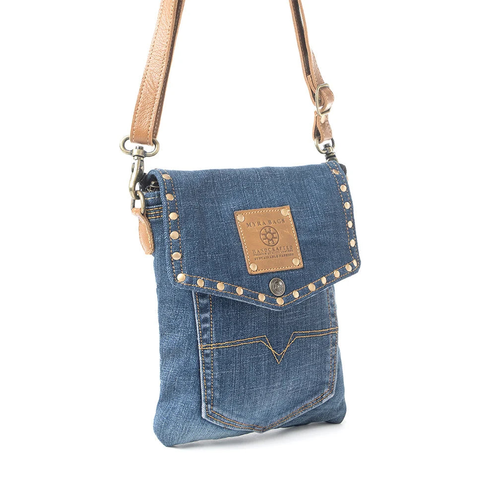 Myra Dahlia Denim Crossbody Bag with blue upcycled denim, brass stud accents, leather flap detail, and shoulder strap side view