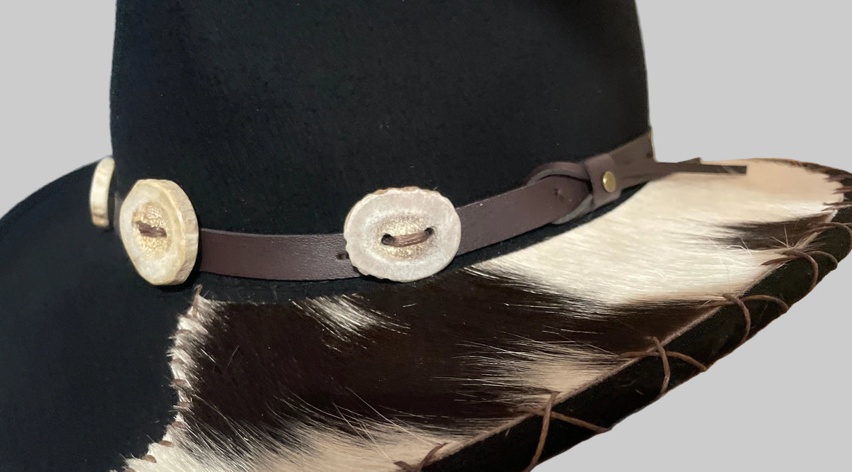 Side view of a black Scala 100% wool western hat with a brown leather band, deer horn buttons, hand-sewn cowhide brim and brown stitching